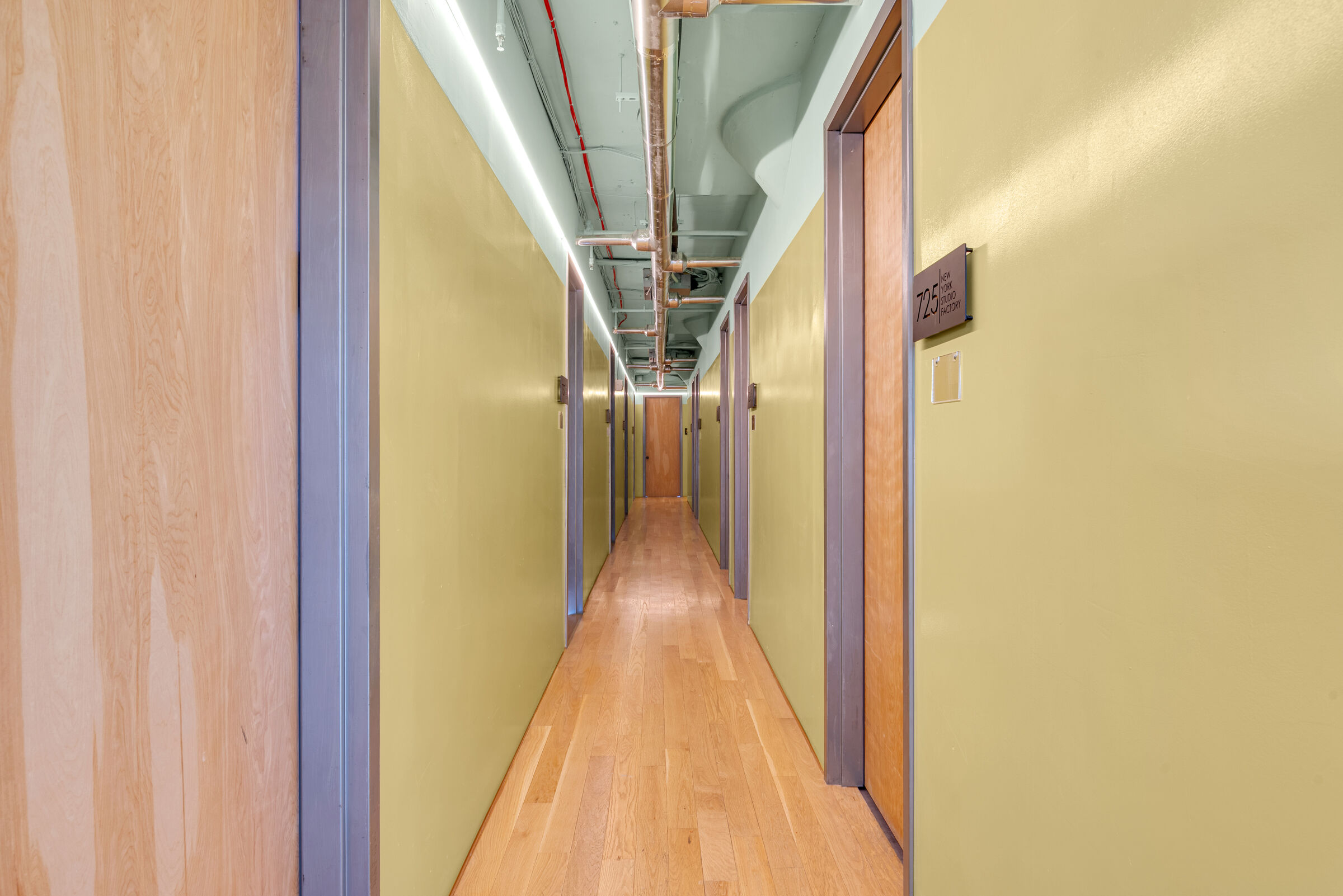 A sage-green corridor leading to numbered nail studios.