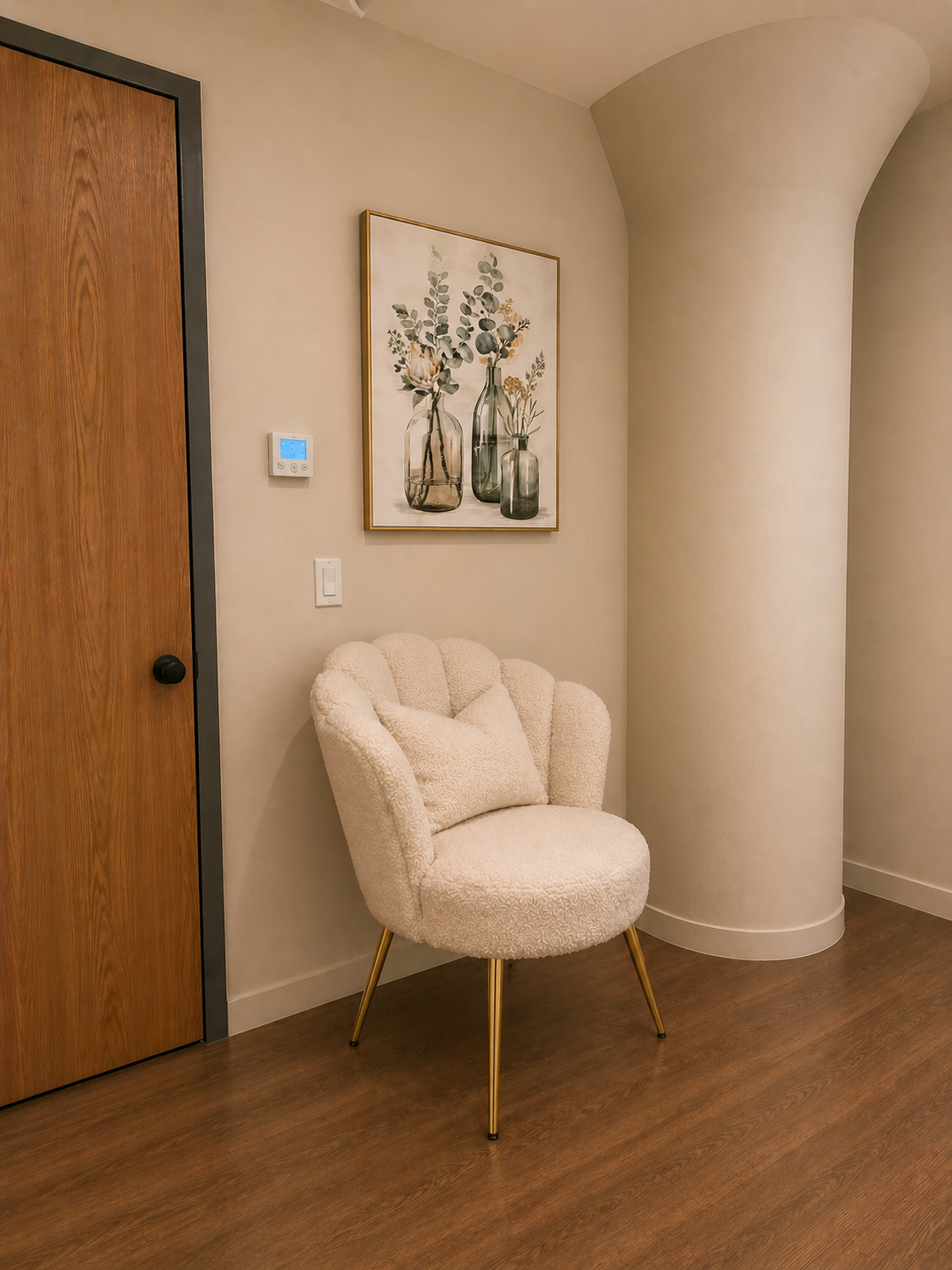 Facial & Waxing entry: a boucle shell chair beneath framed eucalyptus art, with a wood door and digital climate thermostat.