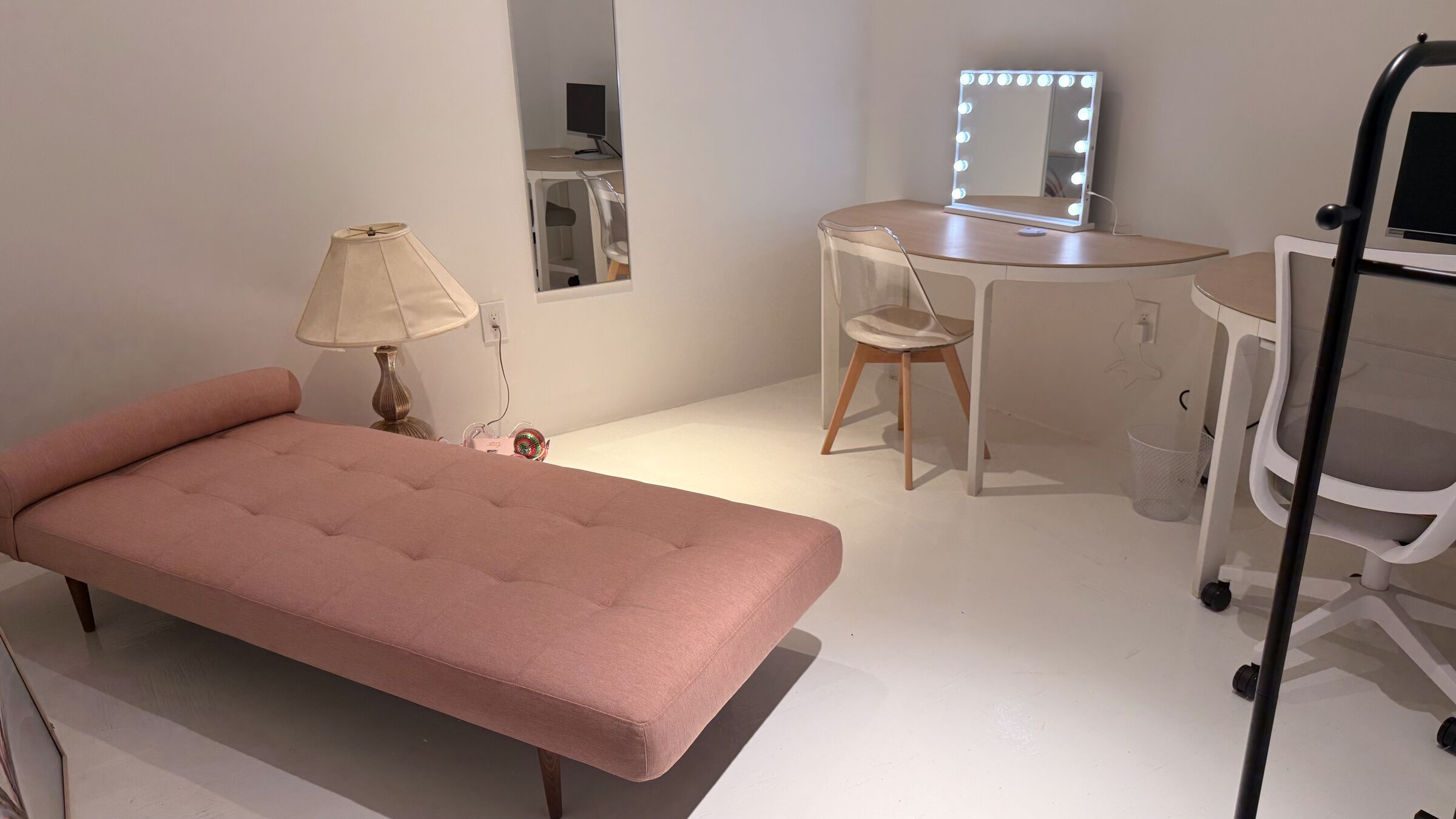 The Makeup Studio (Beauty & General): pink daybed, lit Hollywood-style vanity, half-moon work desks with monitor, and clothing rack.
