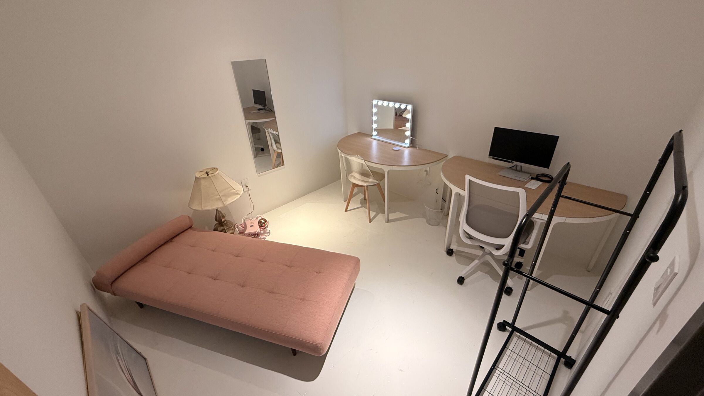 The Makeup Studio: overhead-angled wide showing the full layout — daybed, vanity, monitor desk, and clothing rack.