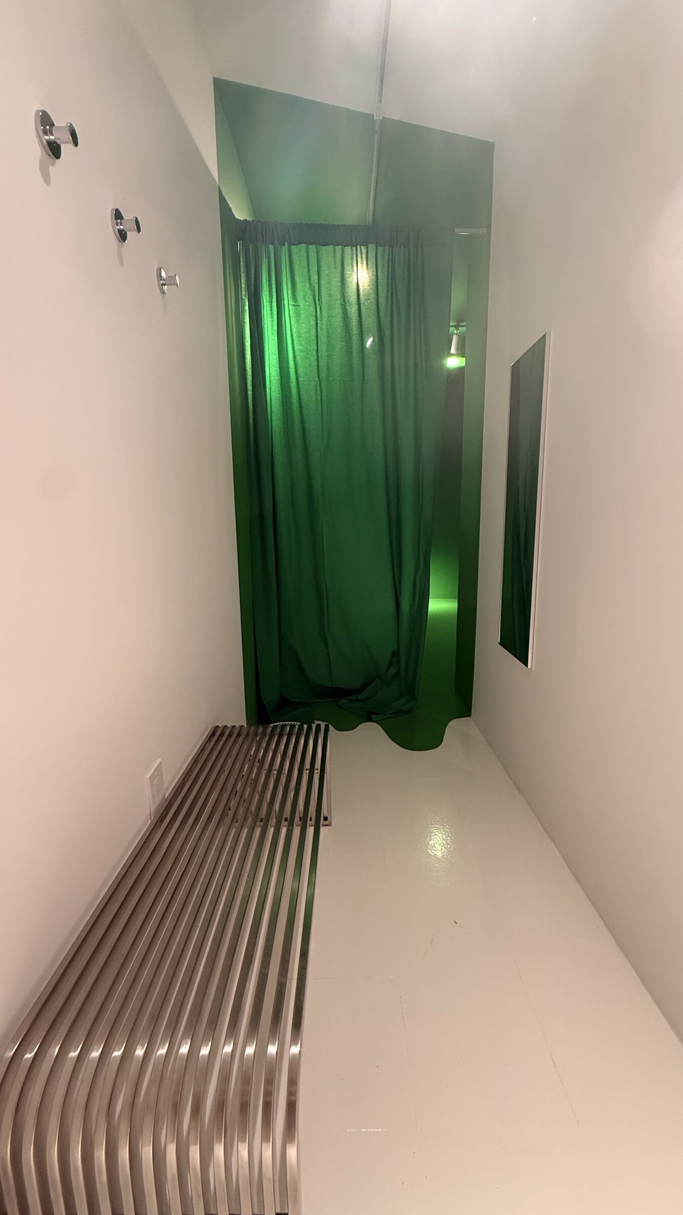 Vertical view of the chroma-green entrance curtain with the stainless bench in the foreground.